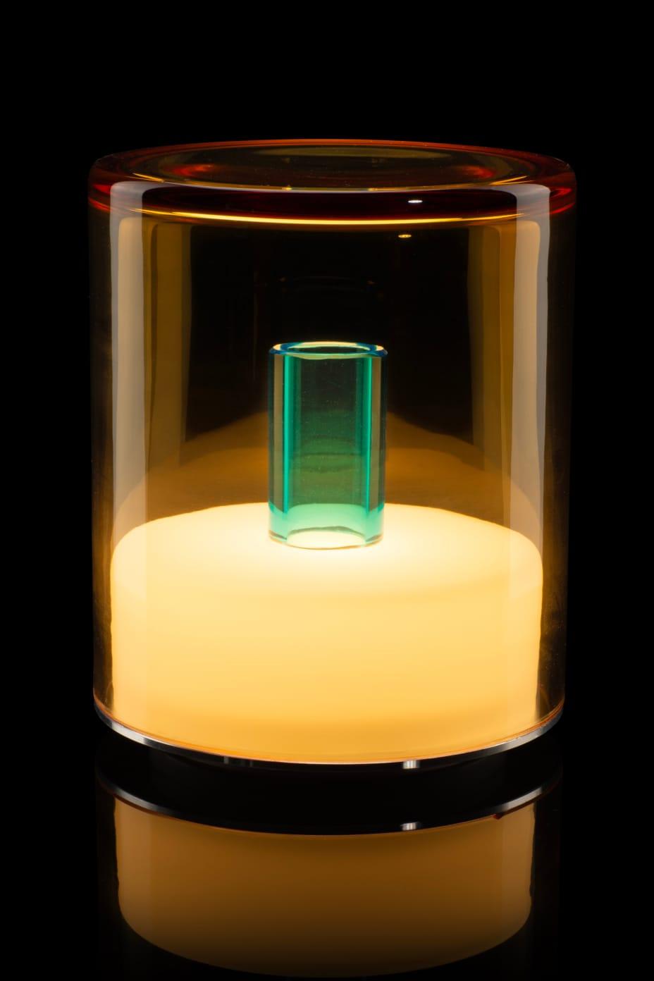 Glass container with a glowing green object inside on a black background
