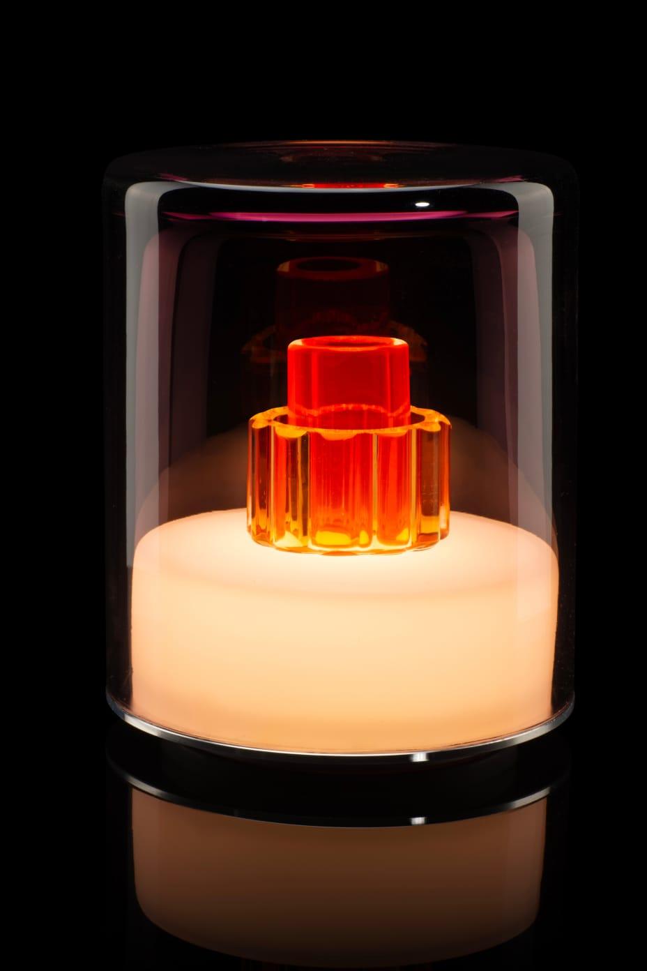 Glass container with a red and orange object inside on a black background