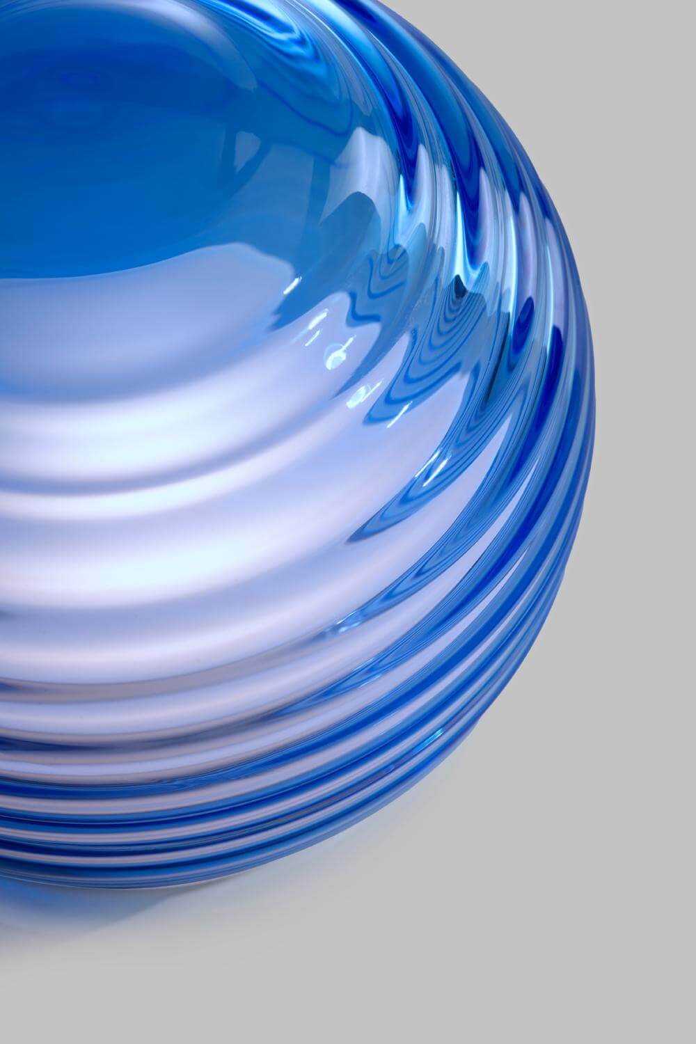 Blue curved glass table light with patterns on a grey background