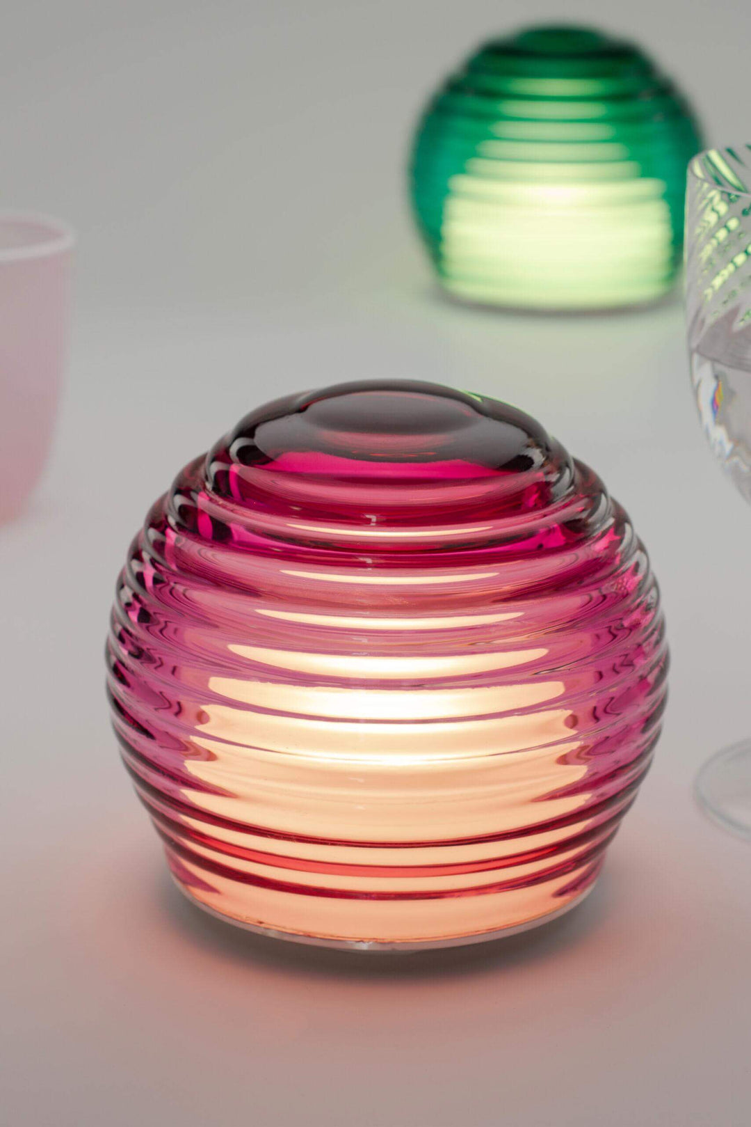 Pink glass lantern with ribbed design on a white background