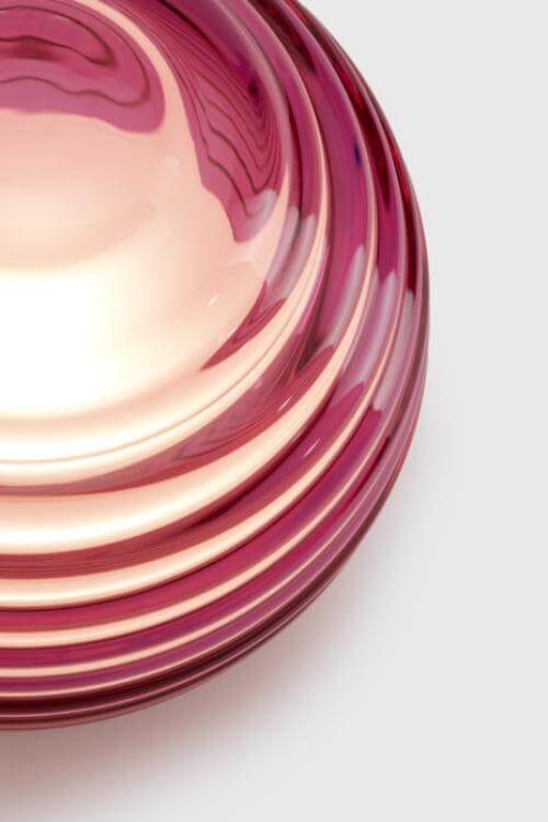 Pink glass lantern with ribbed design on a white background