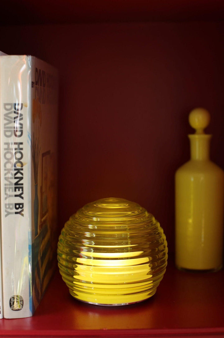 Yellow glass orb and bottle on a shelf with a book titled &