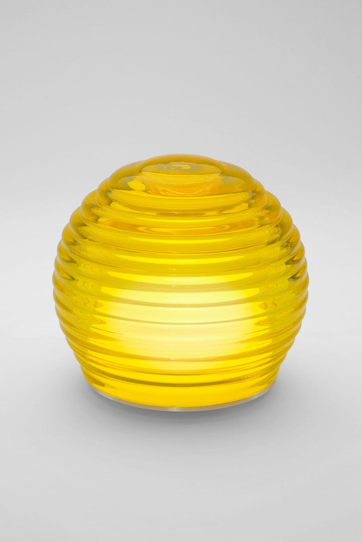 Yellow glass object with ribbed texture on a gray background